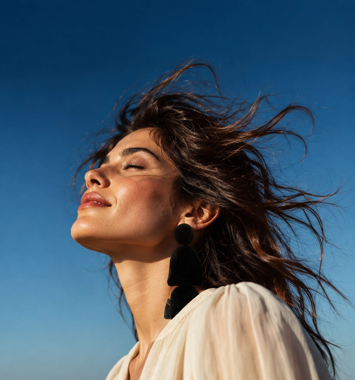 A woman outdoors with her face turned toward the sun